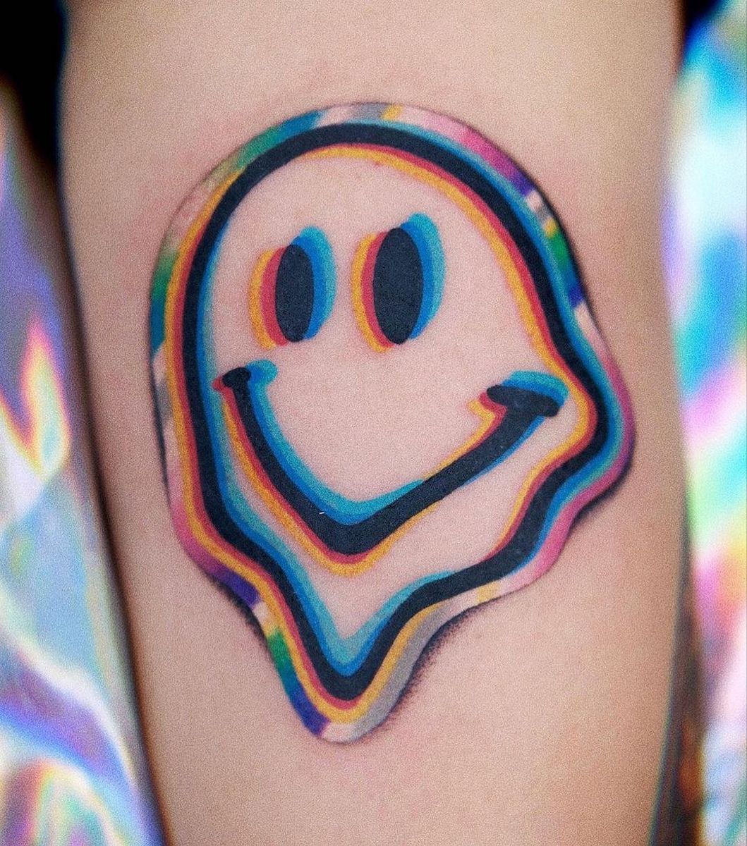 Colorful melting-style smiley face tattoo on forearm with rainbow trippy outline