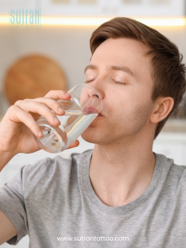Drinking water to stay hydrated before getting a tattoo
