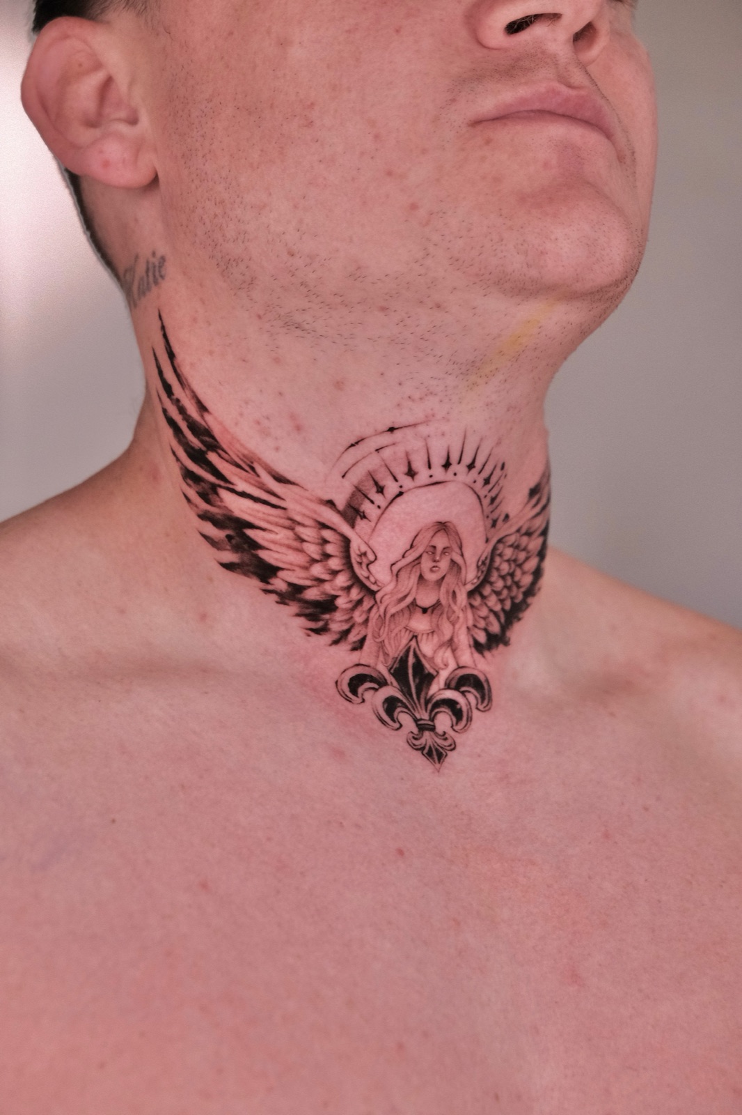 Angel figure with wings and halo tattooed across the front of the neck and throat