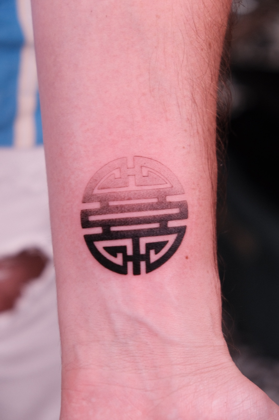 Blackwork circular Asian longevity symbol tattoo on the wrist