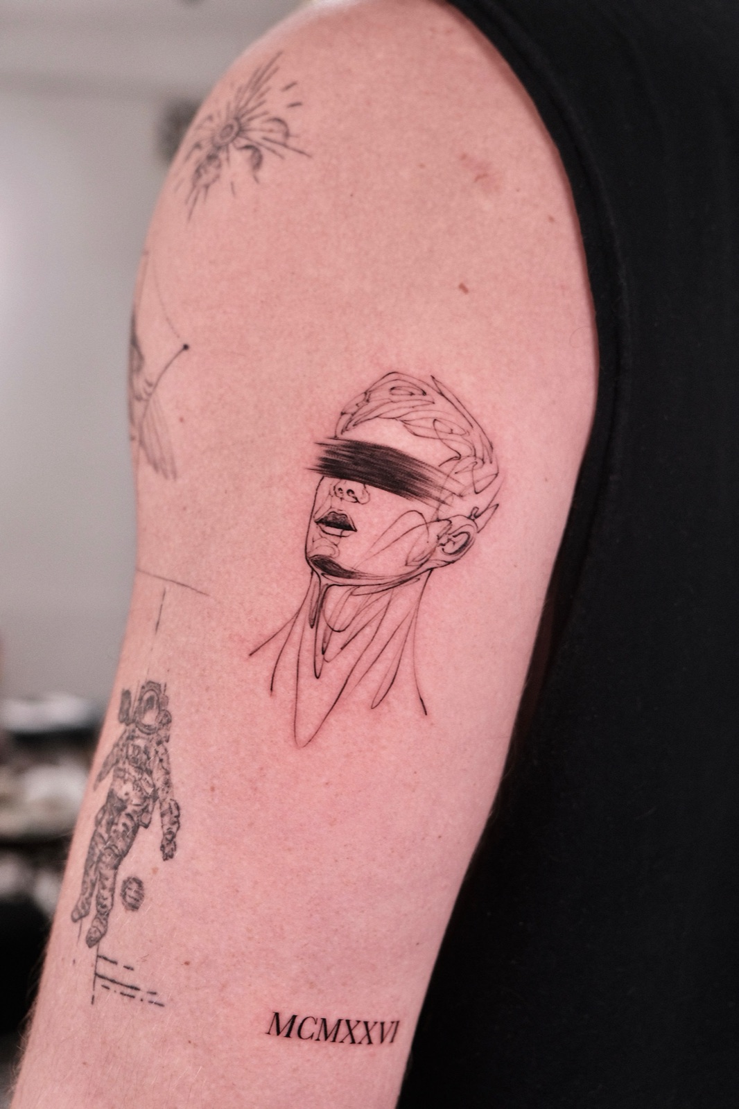 Black and grey portrait tattoo of a blindfolded woman on the forearm