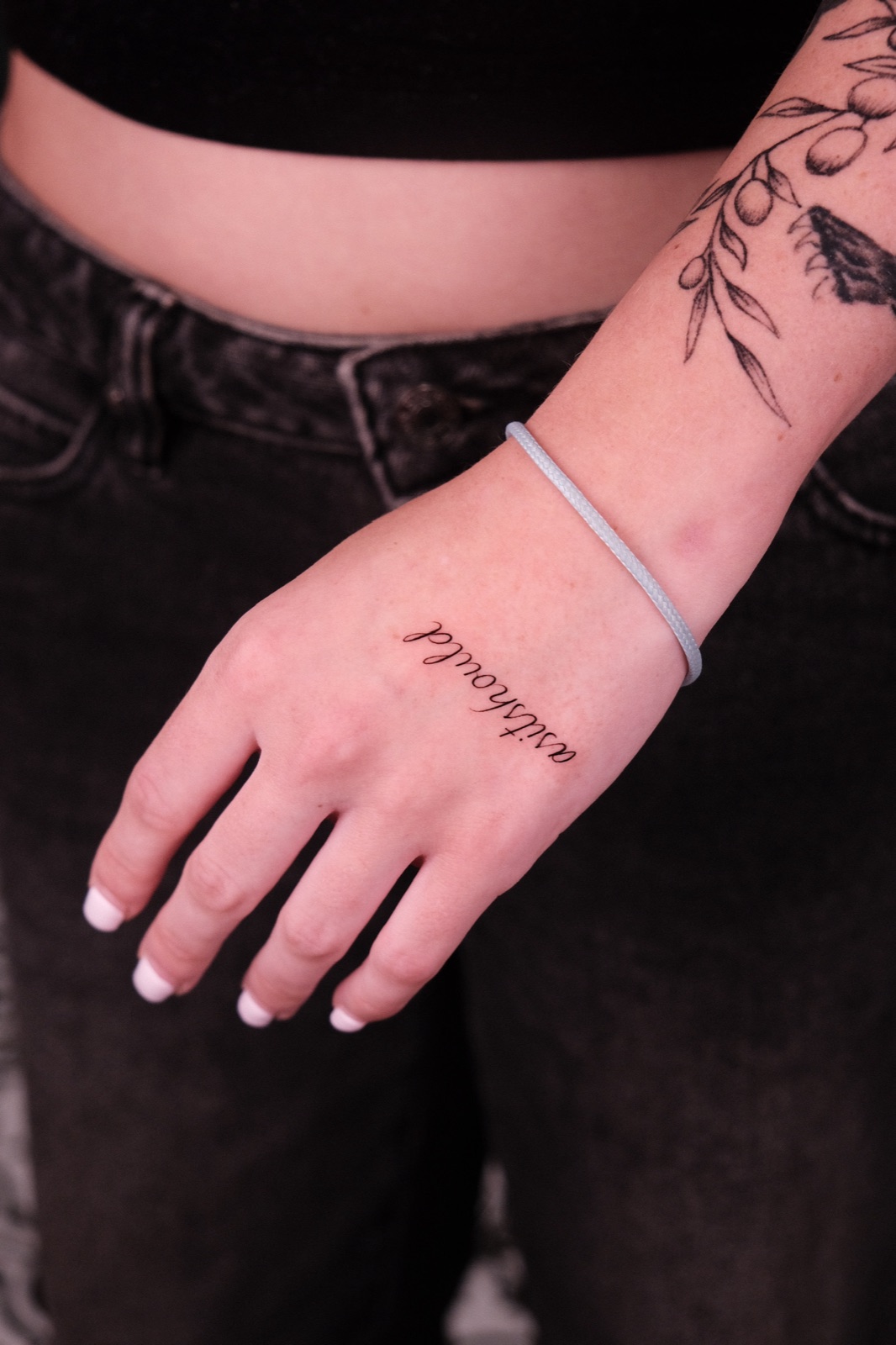 Cursive script lettering tattoo on the back of the hand