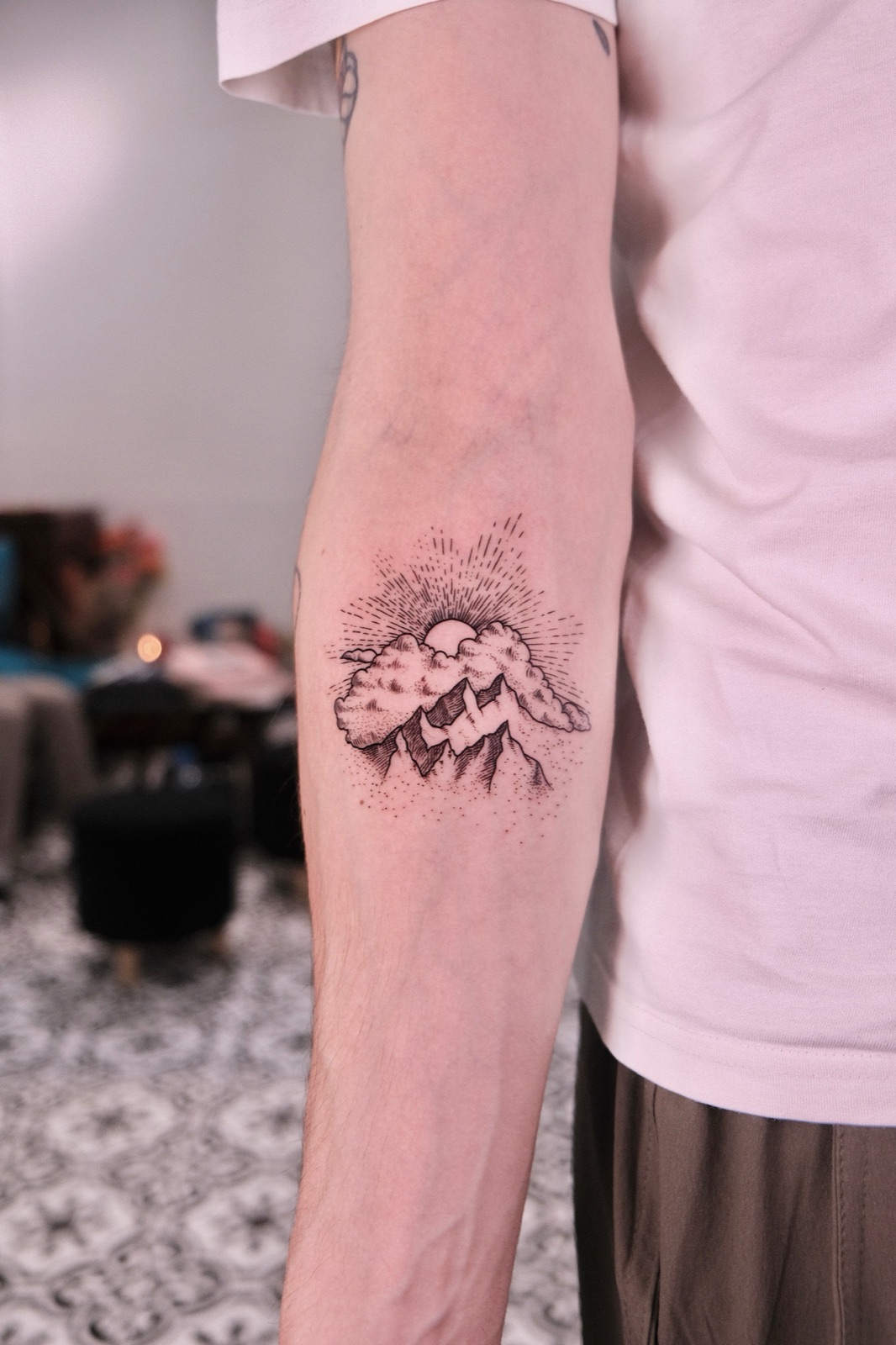 Dotwork mountain and sunburst tattoo on the forearm