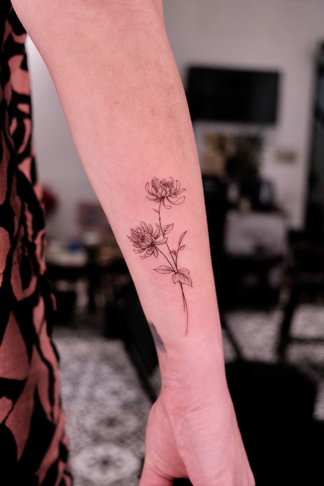 Fine line chrysanthemum flower tattoo on the forearm
