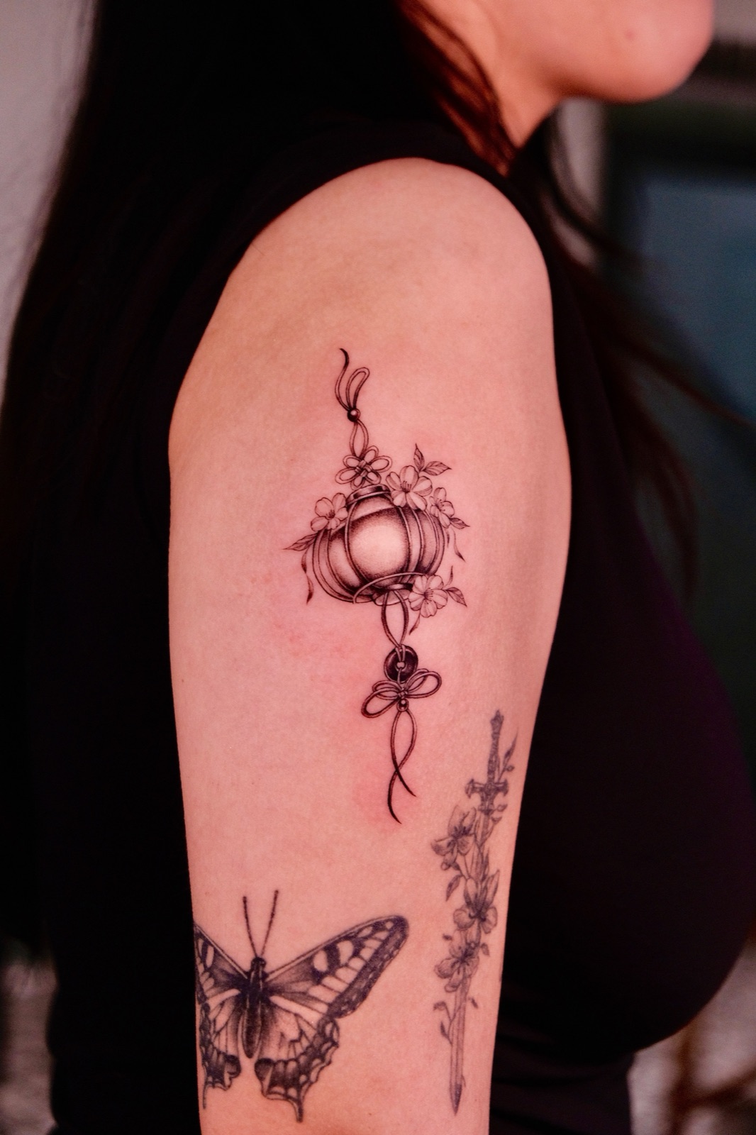 Fine line floral lantern tattoo on the upper arm