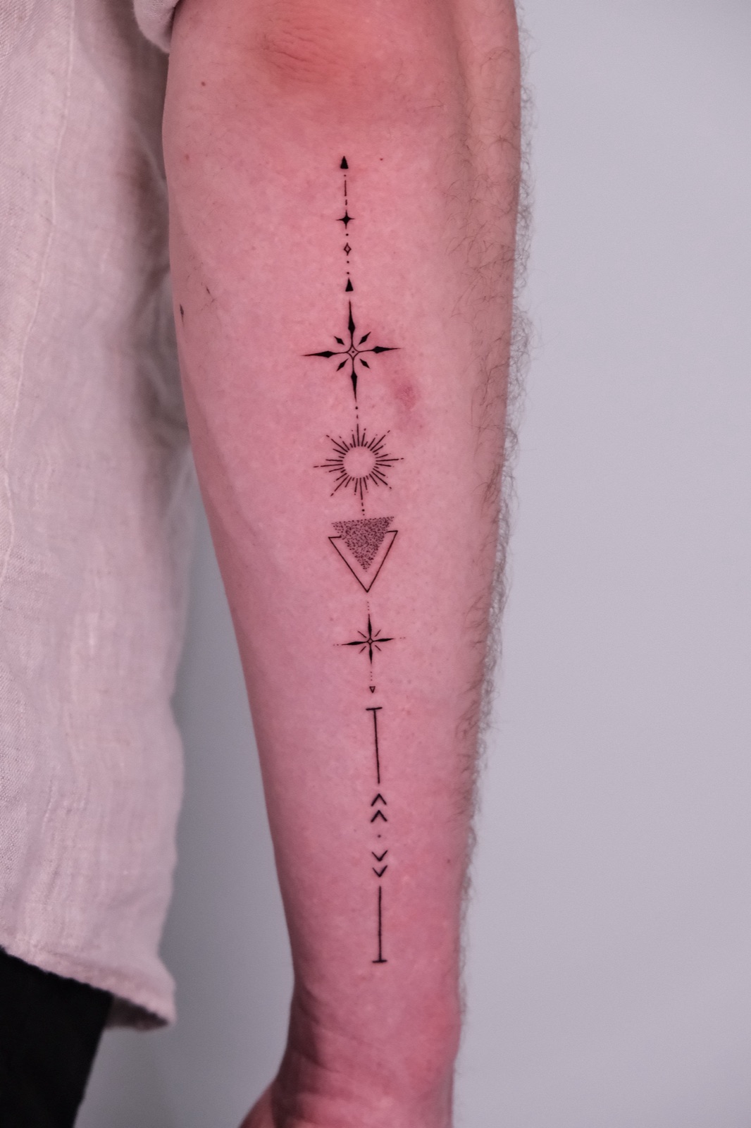 Geometric symbol chain tattoo on the forearm