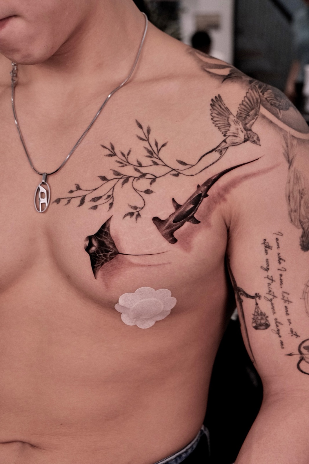 Black and grey hammerhead shark and manta ray chest tattoo with a bird on a branch