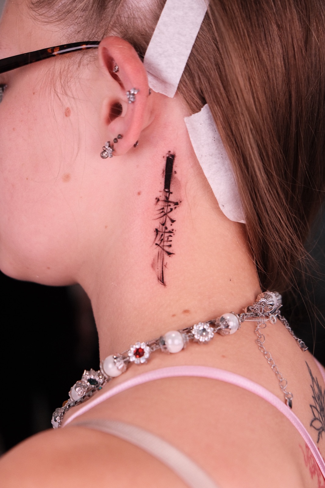 Back of neck Japanese calligraphy tattoo with a sword brush-stroke design