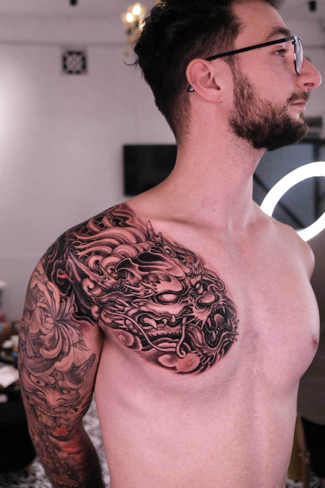 Large black and grey Japanese dragon head tattoo covering the chest and shoulder