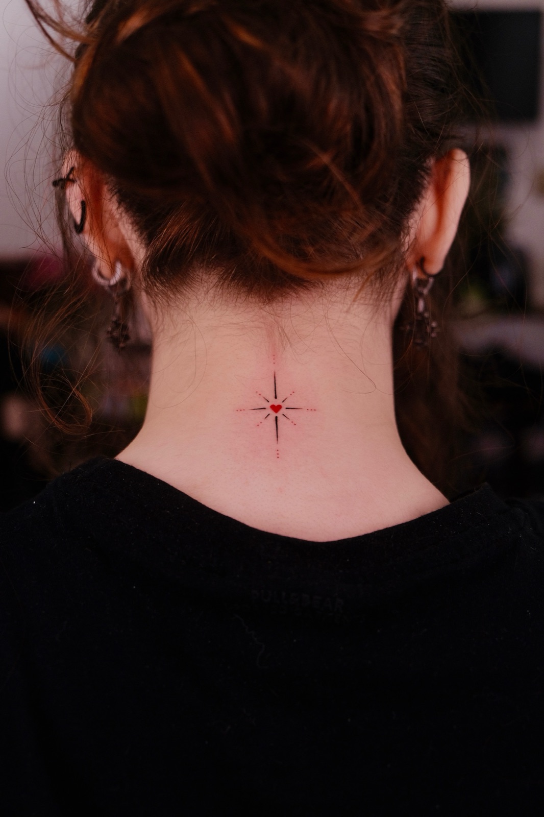 Minimalist compass star with a small red heart tattooed on the back of the neck