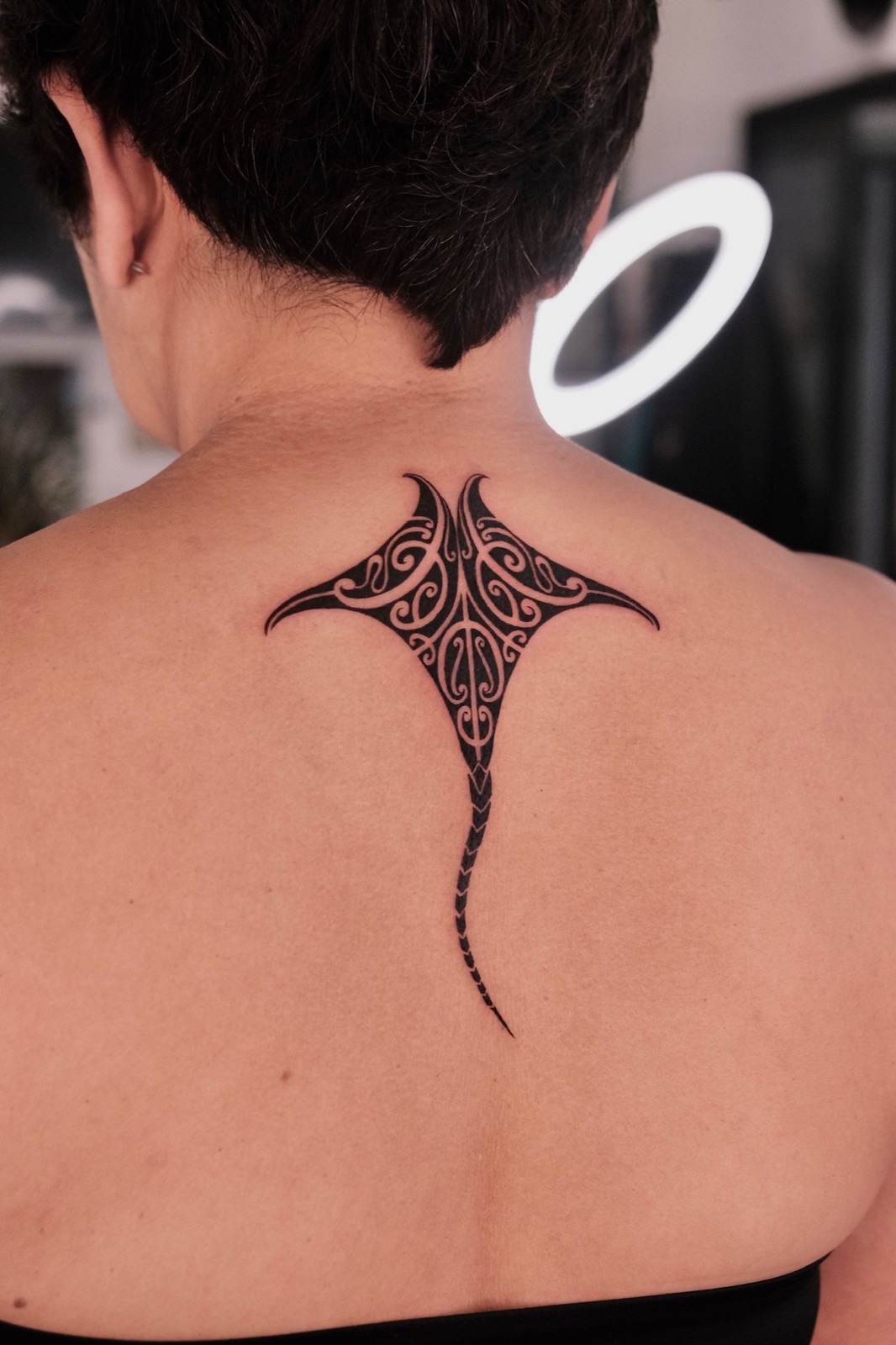 Bold Polynesian-style tribal manta ray tattoo extending across the upper back and neck