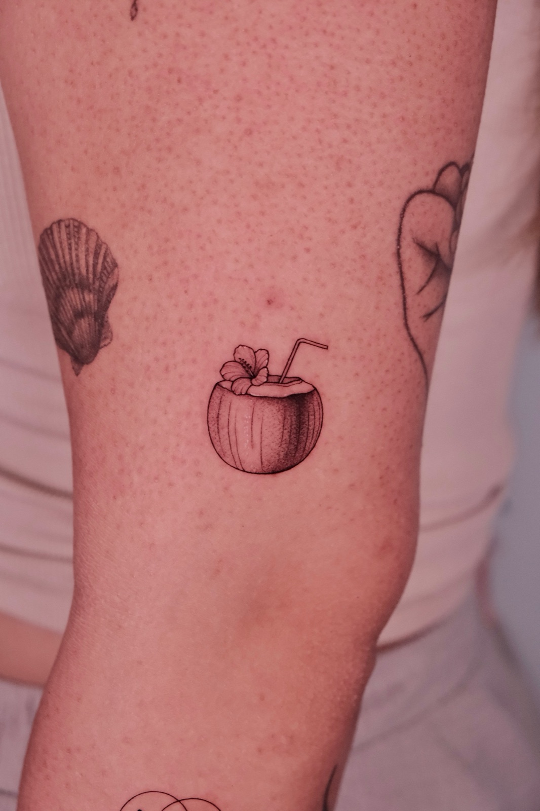 Tattoo of a tropical coconut drink with a hibiscus flower and straw on the arm