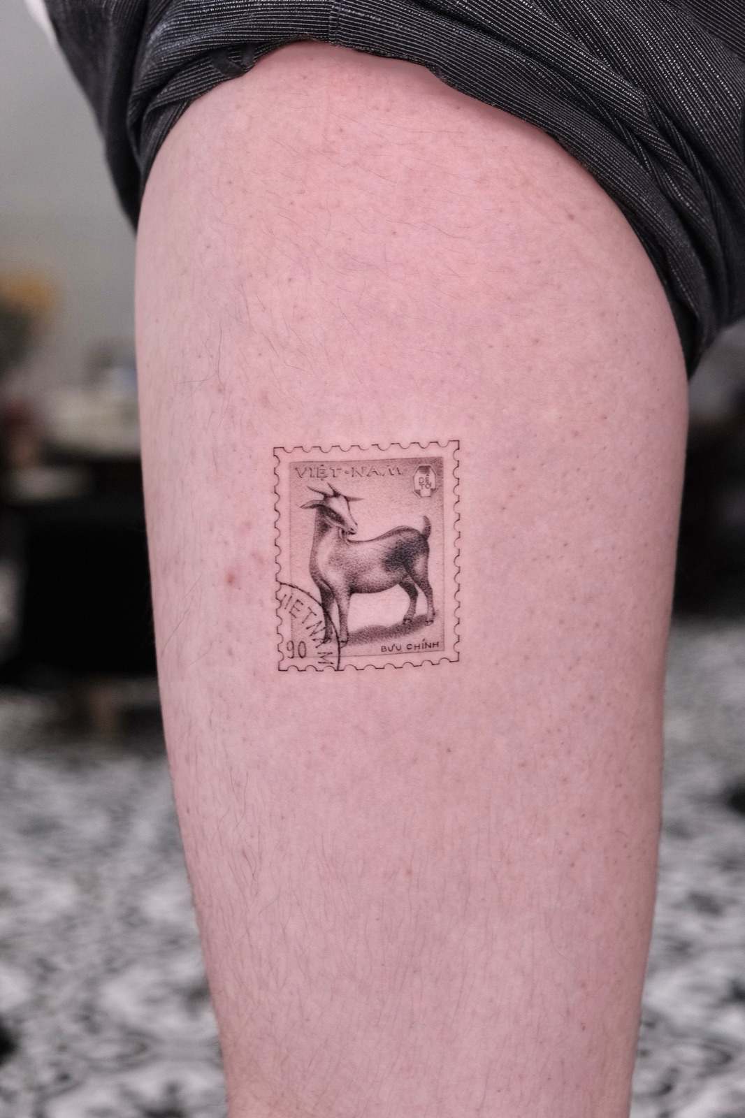 Realistic tattoo of a Vietnam postage stamp featuring a goat