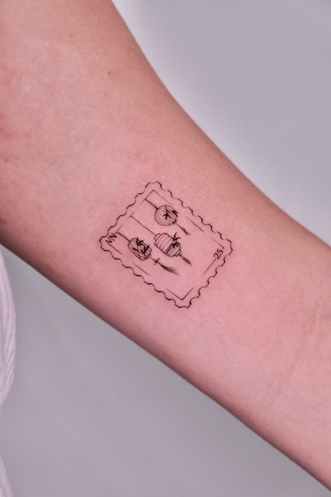 Vietnam postage stamp tattoo featuring a lantern design on a forearm