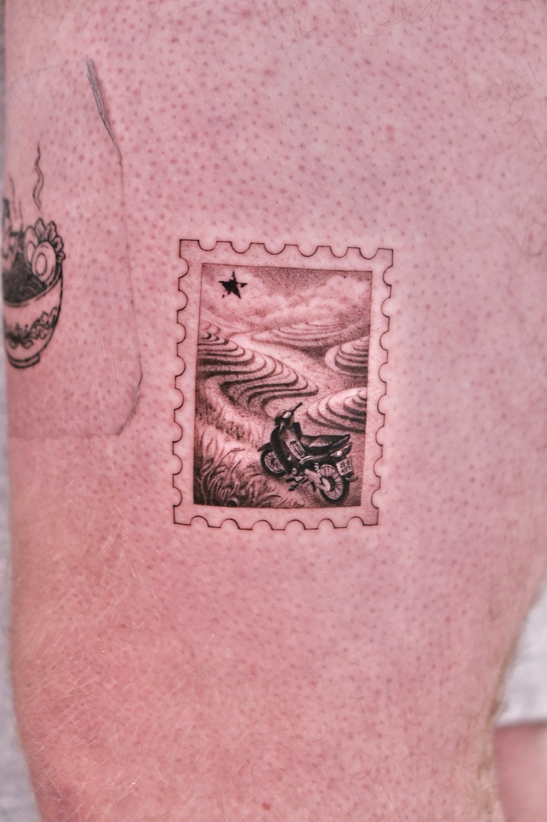 Fine-line Vietnam postage stamp tattoo with a motorbike on rice terraces, forearm