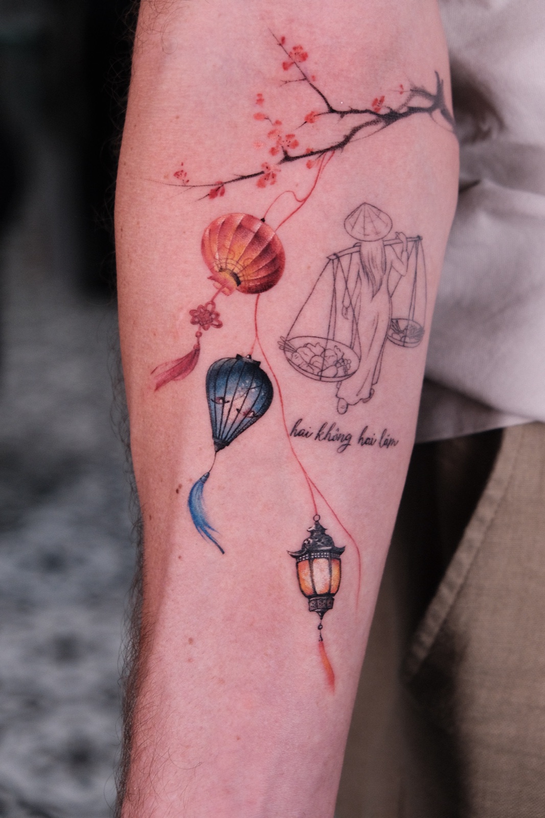 A colorful Vietnamese-themed sleeve tattoo with a cherry blossom branch, hanging lanterns, and a street vendor carrying a shoulder pole