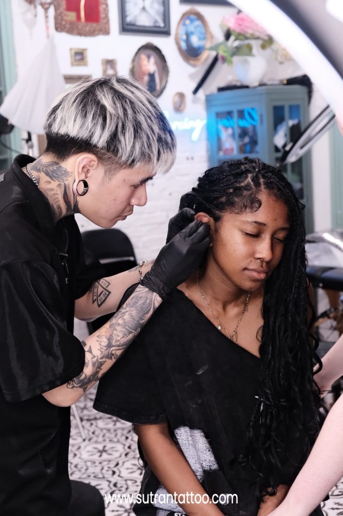 Body piercing in Ho Chi Minh City - gloved piercer performing a sterile ear piercing at Sutran