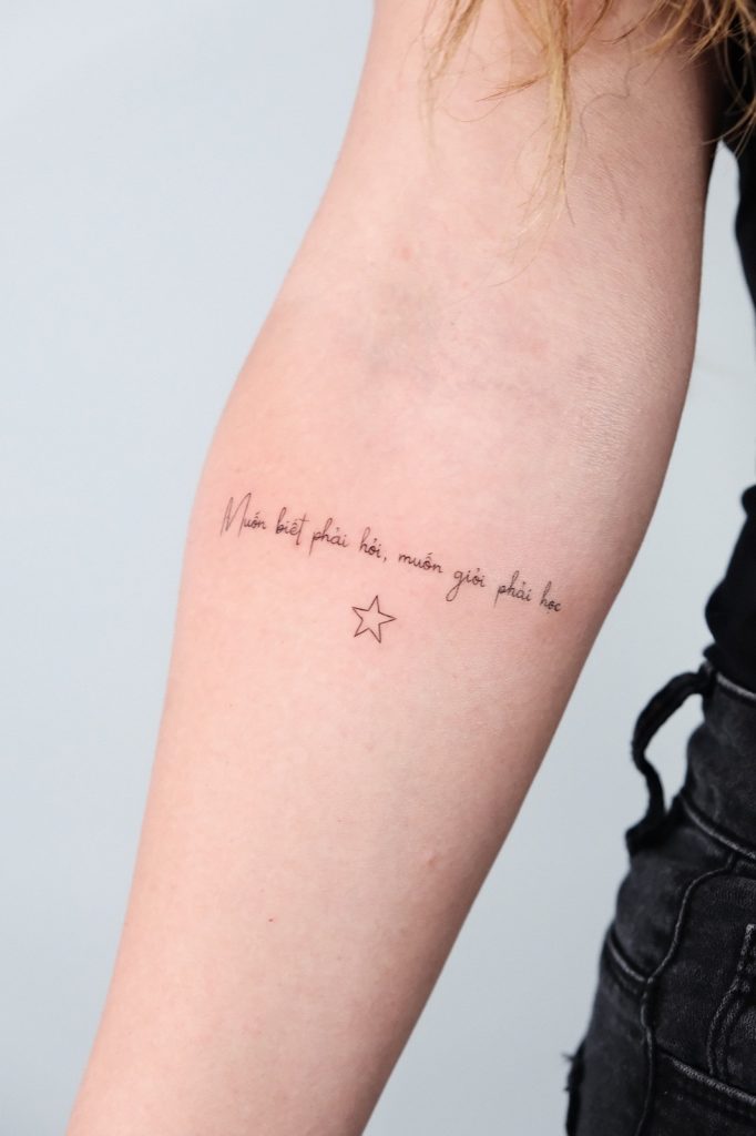 Fine-line script quote with a small star tattooed on the inner forearm
