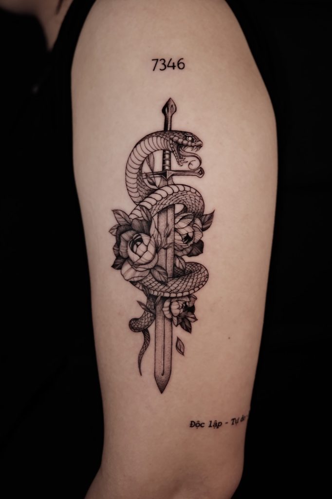 Fine-line snake wrapped around a dagger on the upper arm