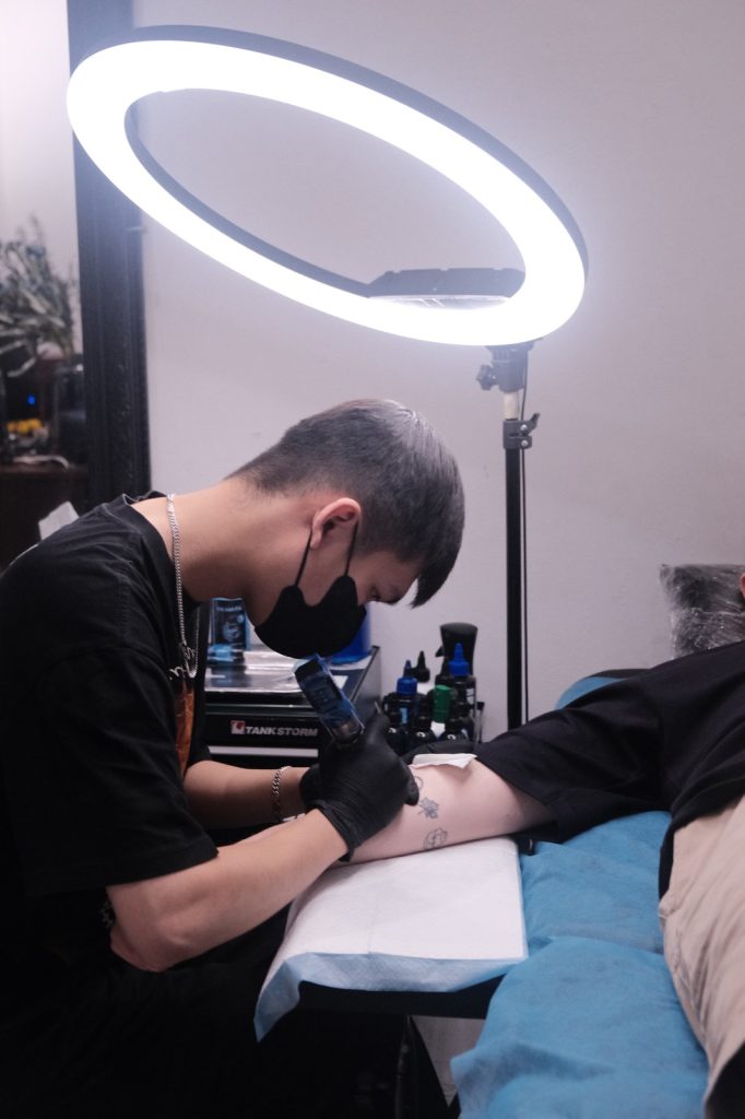 Tattoo artist working on a client's forearm at Sutran Tattoo studio