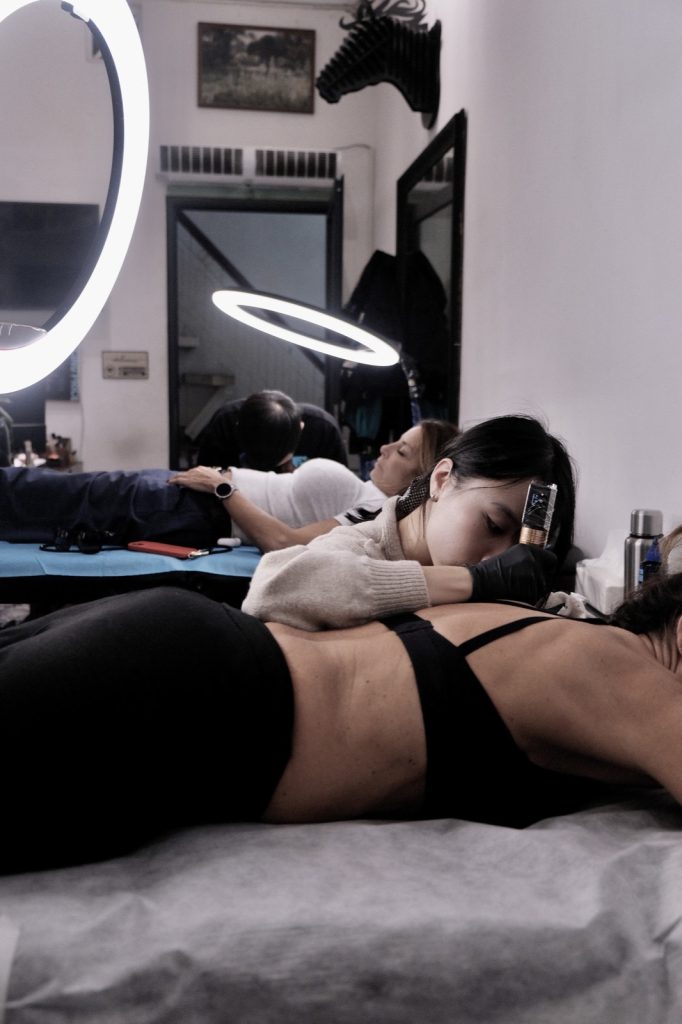 Client lying face down in a sports bra during a lower back tattoo