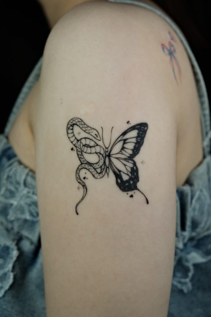 Butterfly tattoo with a snake forming its body on the shoulder
