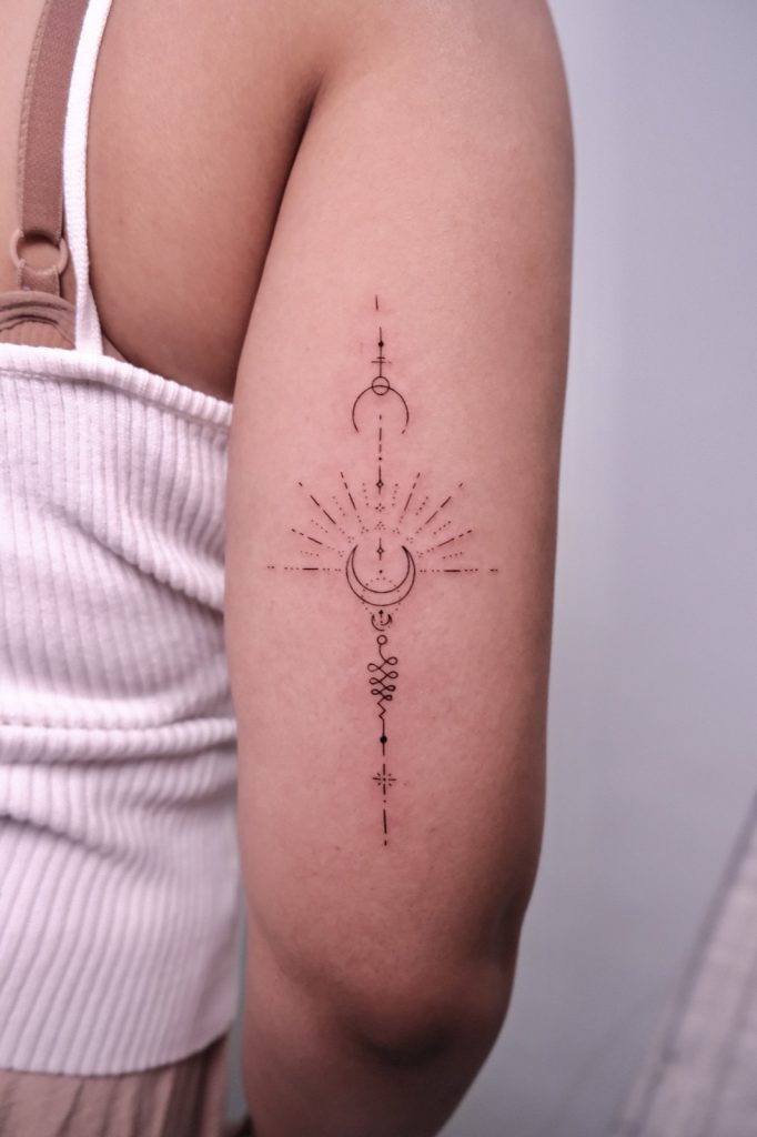 Unalome with crescent moons and sun rays on the upper arm