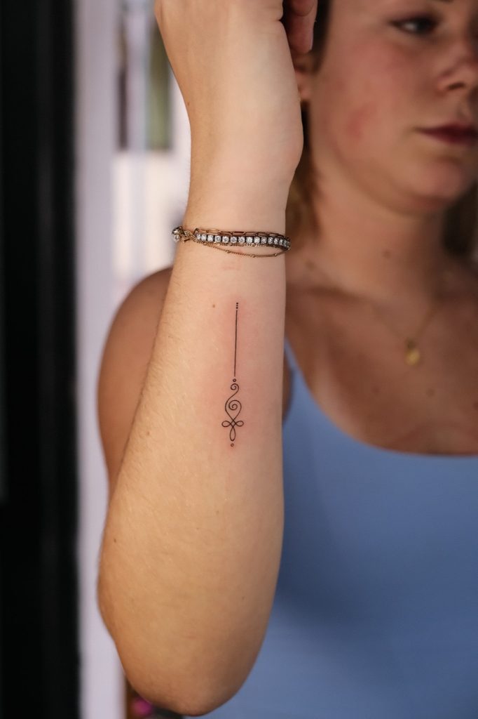 Fine-line unalome tattoo on the inner wrist