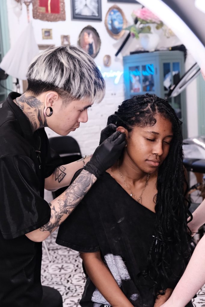 Artist preparing a neck tattoo while the client holds her hair aside