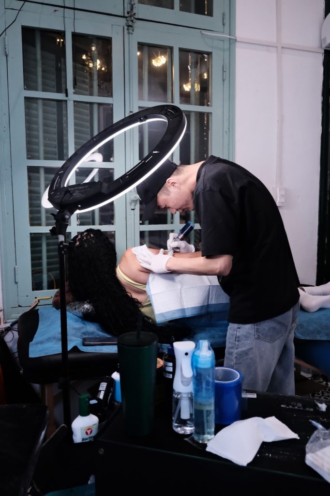 Tattoo artist working on a client lying on the tattoo bed