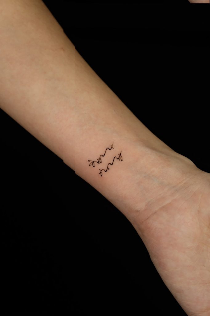 Tiny fine-line script tattoo on the side of the wrist