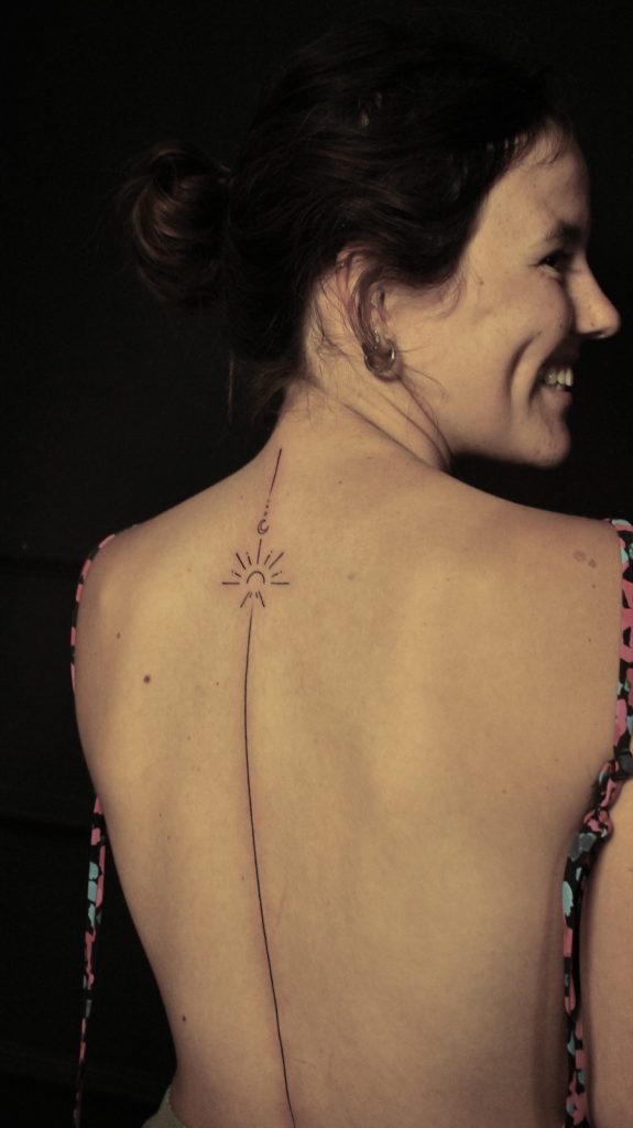 Long fine-line unalome with a sun running down the spine
