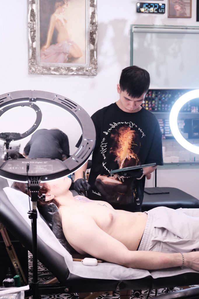Client lying on a tattoo bed in shorts during a session